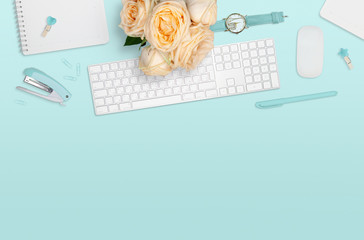 Flat layout of workplace with bouquet of roses on mint background