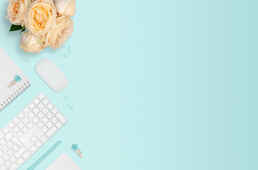 Flat layout of workplace with bouquet of roses on mint background