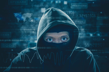 Hacker works with mask and looking at binary code