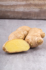 Fresh ginger root, whole and sliced on grey background, vertical format.