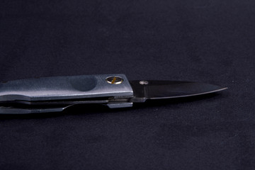 small pocket knife on black background with sharp blade