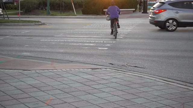 Mexican Cyclist Crossing Traffic On Bicyle With Cars Weaving In And Out And Some Grafitti On Sidewalk