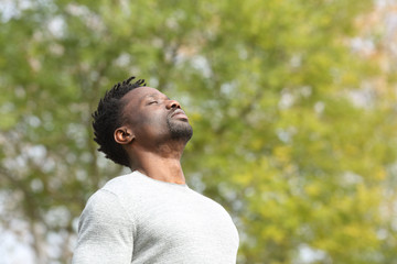 Black serious man breathing fresh air in a park