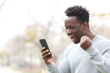Excited black man celebrating mobile phone news