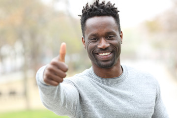 Happy black man gesturing thumbs up outdoors