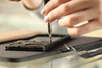 Woman removing screws on a smart phone on a desk