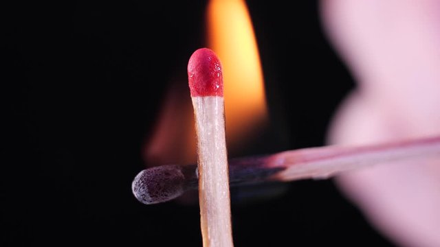 Macro footage 50fps, close up of igniting a match using another match. Isolated burning match on black background. Very detailed macro stock. Concept: occupational burnout, fire flames