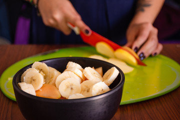 Fresh and delicious fruit in a bowl while a person is cutting apples