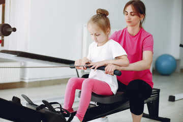 Mother with daughter in a gym. Little girl are engaged in gymnastics