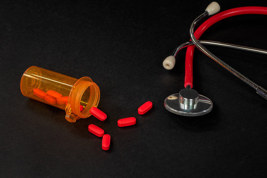 Red Pills In Orange Prescription Bottle With Medical Stethoscope 