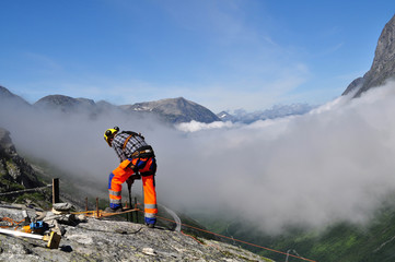 Obraz premium A man working on a rock in the mountains above a deep valley (Norway)