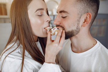 Cute couple in a kitchen. Lady in a white shirt. Pair at home