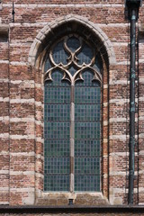 Fototapeta na wymiar Pointed ogive arch with gothic window at the brick facade of Goes city church in the Netherlands