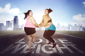 Two young overweight woman jumping outdoors