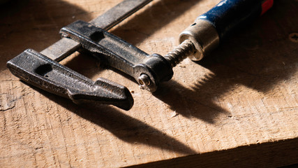 Clamp tool on a wooden background.  F-clamp, bar clamp, speed clamp and a G-clamp.