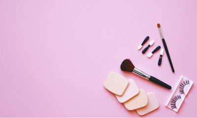 Professional makeup tools. Makeup tools brushes, eyelashes, nail polish, creme ,cotton pads, perfume, applicators on pink  background. Cosmetics for beauty.Top view with copy space Flat lay.