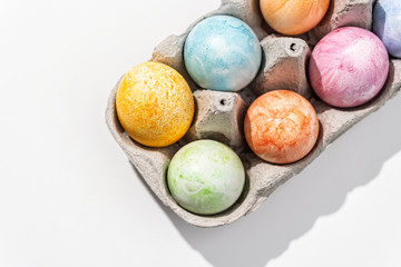 Painted Easter eggs in an egg tray. White background. Top view.