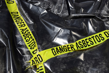 Asbestos warning tape over a pile of affected asbestos product