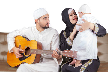 Young muslim parents and their son playing guitar