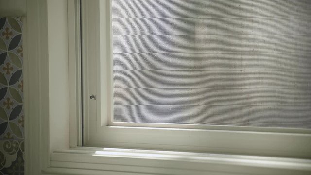 Hand closing mosquito net and then glass door on window
