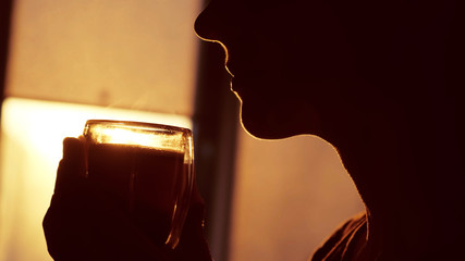 freshly brewed morning coffee in the hands of a woman in the morning sun. she enjoys his delicious smell and aroma