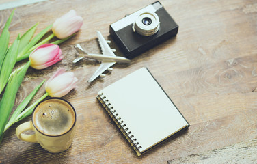 top view image of spring tulips next to old camera, mockup notebook on wooden table
