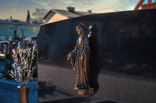 Grabstein mit religi&ouml;ser Figur auf einem Friedhof im warmn Licht
