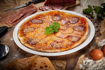 Flatlay of Italian pizza on wooden background. Rustic homemade pizzas with salami, bacon,  cheese, eggs and raw vegetables on shabby wooden background. Healthy vegetarian fungi pizza