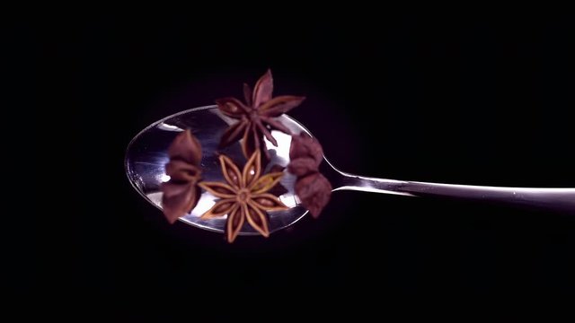 A Full Spoon Of exotic spice anise Flying up and Falling down on black background closeup in super slow Motion