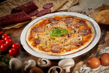 Flatlay of Italian pizza on wooden background. Rustic homemade pizzas with salami, bacon,  cheese, eggs and raw vegetables on shabby wooden background. Healthy vegetarian fungi pizza