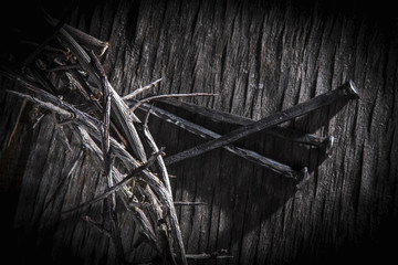 Black and white image of crown of thorns and nails again vintage wooden background as symbol of...