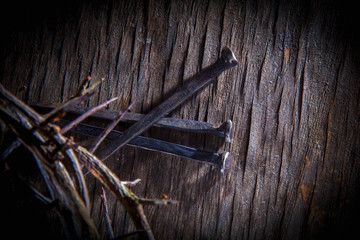 Top view of crown of thorns and nails again vintage wooden background as symbol of crucifixion of...