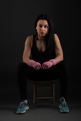 Boxing. Woman boxer sitting on bench wrapping bandage around hand close-up