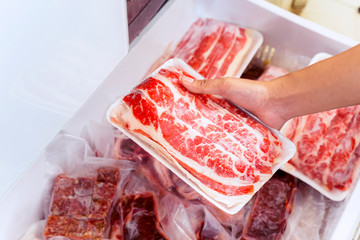 Closeup of human hand picking big chunk red meat