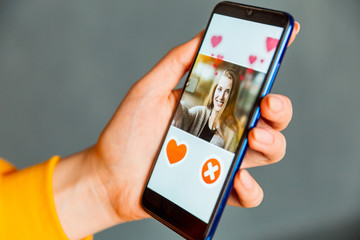Online dating app in smartphone. Person swiping and liking profiles on relationship site or application. Single guy searching for love partner.