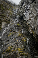 Fototapeta na wymiar Looking up at rock face with water falling to misty mountain edge