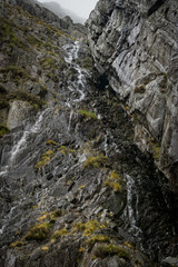 Looking up at rock face with water falling to misty mountain edge