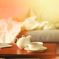 Cozy home interior with teapot, cup of tea and eBook