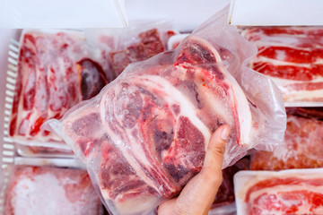 Top closeup of hand picking a pile of red meat