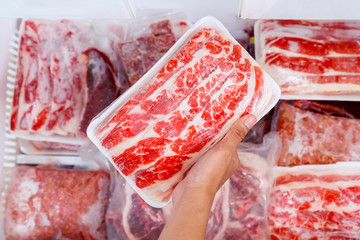 Top closeup of hand picking big chunk red meat