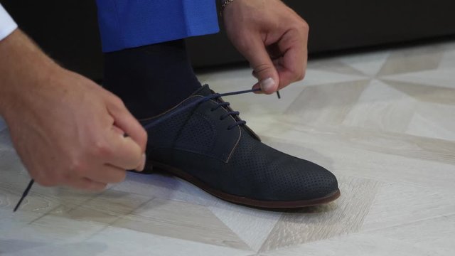 man s hands tied shoelaces. businessman gets dressed for work in morning. Slow motion. beautiful fashionable shoes are put on by person.