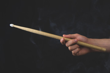 Hand holds wooden drumstick in the dark