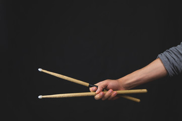 Hand holds drumsticks in the dark. copy space