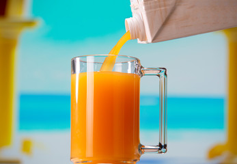 Apricot juice pouring from a juice carton into a mug