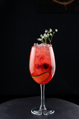 Red vermouth cocktail with cucumber and cherry isolated on black background