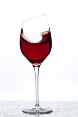 Close up view of splashing red wine in glass isolated on white background. 