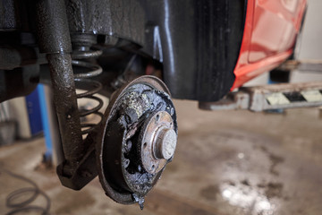 Rusty drum brakes, rear on red car. Change the old to new brake disc on car in a garage. Auto...