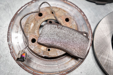 Old used and new to change for safety car brake disc and pad on metal table of an auto mechanic. Auto repair concept. © malkovkosta