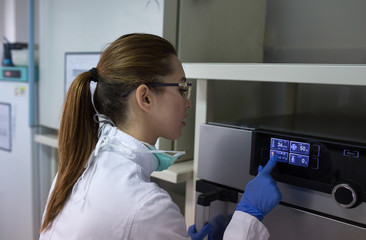 Biologist working on display of incubator in laboratory