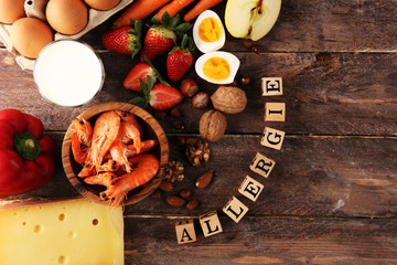 Allergy food concept. Allergy food as almonds, milk, cheese, strawberry, eggs, peanuts and .crustaceans or shrimps with wooden letter in german allergie